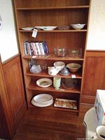 Wood shelving unit front with six shelves showing various dishes and glassware (contents not included).