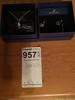 Swarovski earrings and necklace in original packaging with MaxSold lot tag in front.