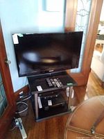 Samsung 46-inch TV on a small stand with various cables nearby.