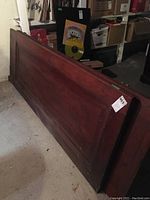 Two solid mahogany interior doors placed on floor showing full length and panel details with moderate wear.