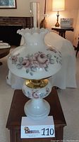Front view of Aladdin decorative hurricane lamp with hand-painted roses on white glass, showing full lamp assembled on wooden table.