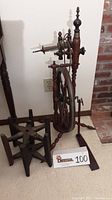 Full side view of the antique wooden spinning wheel showing the drive wheel, flyer assembly, and treadle.