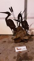 Full view of the sculptures showing two cranes and cattails mounted on the wood base, highlighting size and construction.