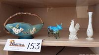 Full view of shelf with Roseville dogwood basket, Cow Parade cow, Lenox rooster, and Lenox bud vase