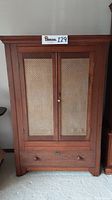 Front view of wooden armoire stereo cabinet showing double mesh doors and bottom drawer.
