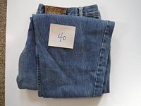 Folded blue denim jeans with size '40' note visible on top