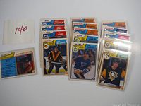 Photo showing 18 vintage hockey cards with player photos and team logos arranged in stacks and laid out, including Tiger Williams and players from Jets, Canucks, Nordiques, Blues, Penguins, Rangers, Flyers teams.