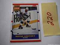 Front of the 1990 Score Wayne Gretzky Season Leader Assists hockey card with image of Wayne Gretzky skating on the ice in white uniform.