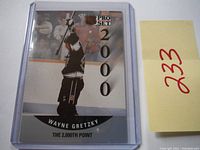 Front view of the 1990 Pro Set hockey card #703 featuring Wayne Gretzky celebrating the 2000th point milestone, encased in a plastic sleeve.