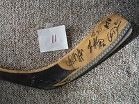 Blade of the hockey stick showing multiple player autographs in black marker.