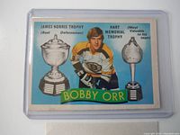 Front of the vintage 1971-72 O-Pee-Chee Bobby Orr hockey card in protective sleeve showing Bobby Orr with trophies.