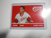 Front of Gordie Howe Detroit Red Wings scoring leader hockey card showing player image and team logo with red background.
