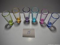 Front view of the six vintage shot glasses in different colors aligned in a row