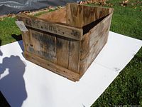 Full image of the antique wooden apple crate showing its rectangular shape, weathered wooden planks and stenciled text on the side.
