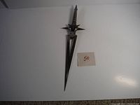 Full view of the 17-inch decorative metal dagger showing blade and handle with star-shaped guard and face motif.