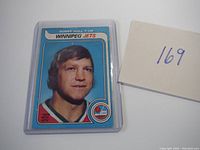 Photo of Bobby Hull hockey card from Winnipeg Jets with blue background, no creases visible, encased in plastic sleeve.