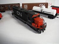 Close-up of the black and red Canadian National diesel locomotive 3068 with adjacent CyanaMid white tank car and brown freight cars.