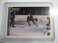 Front view of the vintage Tim Horton tribute hockey card showing Miles Gilbert Horton on ice with other players, with a small tribute logo on the corner. Card is encased in a clear plastic holder.