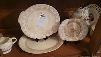 Oval and round plates displayed showing floral pattern with gold trim and visible crazing.