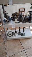 Two shelves displaying various brass decorative items including candlesticks and trays.