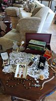 Photo showing the overall collection on a wooden table with butterfly-shaped glass dishes, atomizers, boxes, pins, and various jewelry items