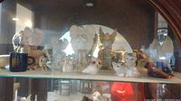 Shelf displaying a variety of angel and cat figurines including small animal sculptures and angelic figures with wings.