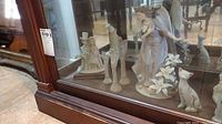 Photo of glass cabinet showing all figurines and plate inside on display shelf