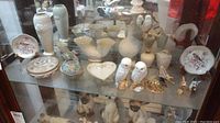Shelved display of assorted porcelain decorative items including Lenox vases, boxes, animal figurines, Royal Worcester plates and cloisonne boxes.