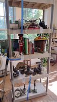 Four-shelf plastic shelving unit with various household items placed across the shelves in natural light.