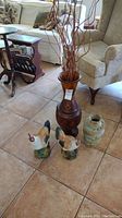 Overview of the lot showing two ceramic rooster figurines and two vases including tall wooden inlaid vase and glazed ceramic vase