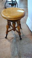 Full view of the vintage wooden swivel piano stool showing round top and turned legs.