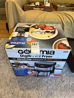 Box of Gourmia Digital Air Fryer with AeroCrisp Technology on a carpet, showing front product image, basic features and branding.