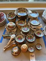 Overview showing multiple stacks of pattern bowls, saucers and spoons on table with blue tape border