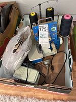 Top view of Baby Lock EF-405 upholstery sewing machine with three large spools of thread mounted, foot pedal visible, manuals and accessories in plastic bags in cardboard box.