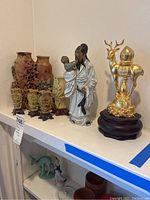 Image showing the soapstone vases, small carved soapstone creatures, porcelain man and child figurine, and gold-colored deer statue on wooden base
