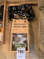 Overhead shot showing Bronnley box filled with coins and paper bills alongside black tray of assorted jewelry