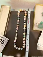 Multicolor pearl necklace placed next to a measuring tape showing length about 18 inches.