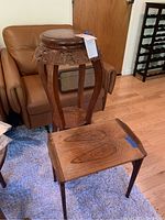 Image showing the vintage Asian tall carved wooden plant stand next to a wooden side table with a natural wood grain surface.