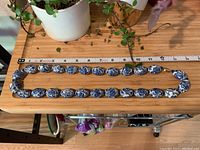 Full view of the porcelain bead necklace laid flat alongside a ruler for length measurement, showing oval beads with blue floral patterns on white porcelain.