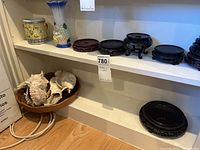 Shelf view showing basket with large seashells and multiple wooden stands for display.