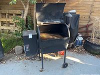 Front view of pellet smoker grill with lid open showing cooking grates and barrel chamber