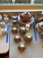 Top-down view of the full set on a table showing the teapot, stack of plates, bowls, cups and saucers arranged in groups.