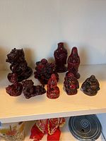 Nine red vintage resin Asian figurines on white shelf
