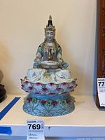 Front view of vintage Chinese porcelain Buddha figurine on lotus base with detailed painting and crown.