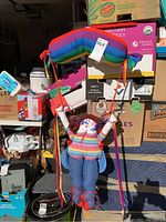 Full view of the soft sculpture rainbow wall hanging held upright with background boxes.