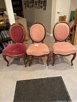 Three matching French-style chairs arranged side by side, two with light pink upholstery, one with darker red upholstery.