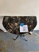 Overhead view of the removable semi-circular black marble table top showing brown and white veining.