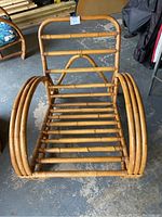 Front view of vintage bamboo arm chair structure without cushions, showing slatted seat and curved armrests.