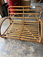 Front view of the bamboo love seat showing slatted seat and back, curved armrests, and bamboo framework.