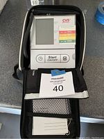 Digital blood pressure monitor with CVS branded cuff laid out out and displayed inside case with quick start guide and manual.